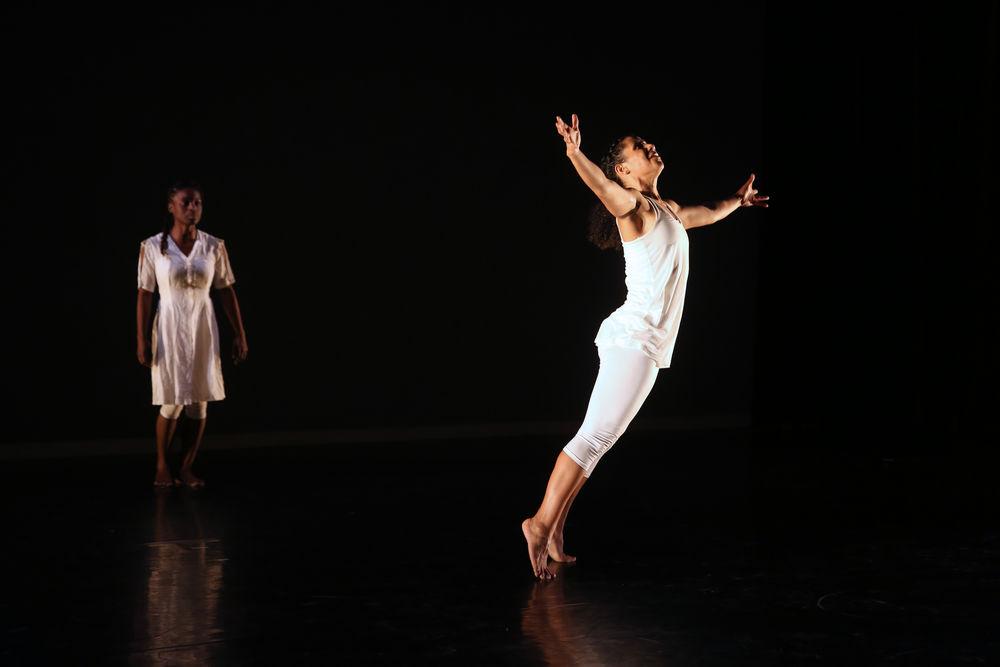 A dancer leaps on stage, with another st和ing behind her. 